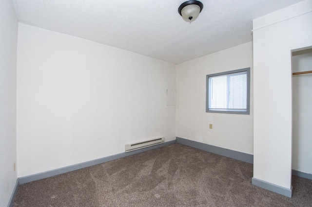 unfurnished bedroom featuring a baseboard heating unit, baseboards, a closet, and dark carpet