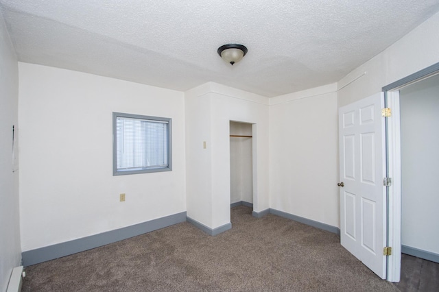 unfurnished bedroom with a baseboard heating unit, baseboards, carpet floors, a closet, and a textured ceiling