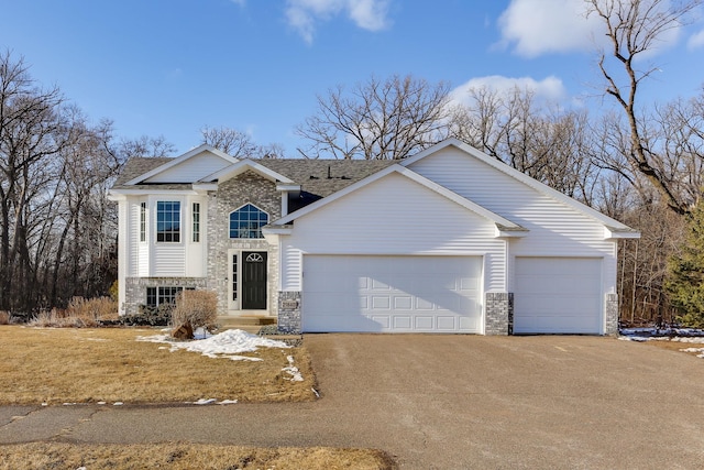 view of front of home featuring stone siding, driveway, roof with shingles, and an attached garage