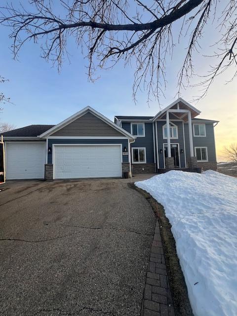 view of front of house with aphalt driveway, stone siding, and a garage