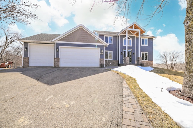 view of front of home with aphalt driveway, stone siding, and a garage