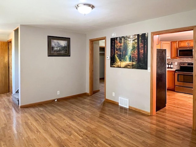 empty room featuring baseboards, visible vents, and light wood finished floors