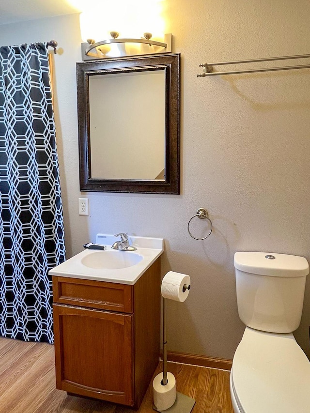 bathroom with vanity, toilet, a shower with shower curtain, and wood finished floors