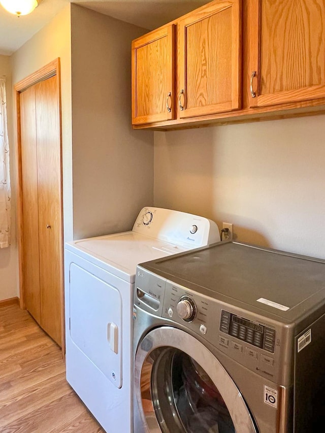 washroom featuring cabinet space, separate washer and dryer, and light wood-style flooring