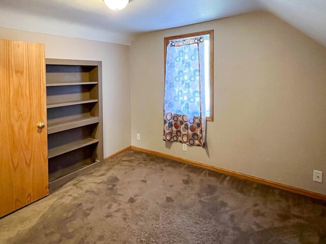 unfurnished bedroom with baseboards, carpet floors, and vaulted ceiling