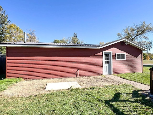 rear view of property with a lawn and metal roof