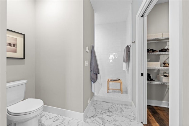 bathroom with baseboards, toilet, and marble finish floor