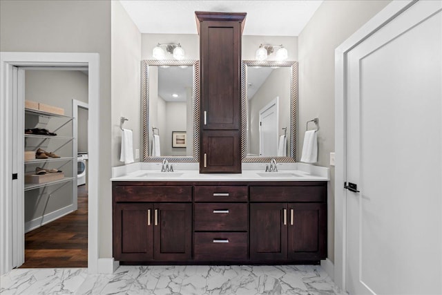 full bath with a closet, marble finish floor, double vanity, and a sink