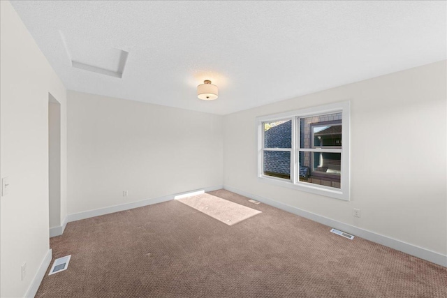 carpeted spare room featuring visible vents, a textured ceiling, and baseboards