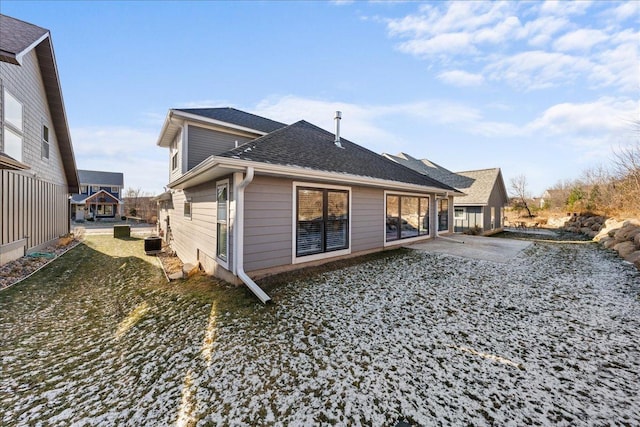 rear view of property featuring cooling unit and roof with shingles