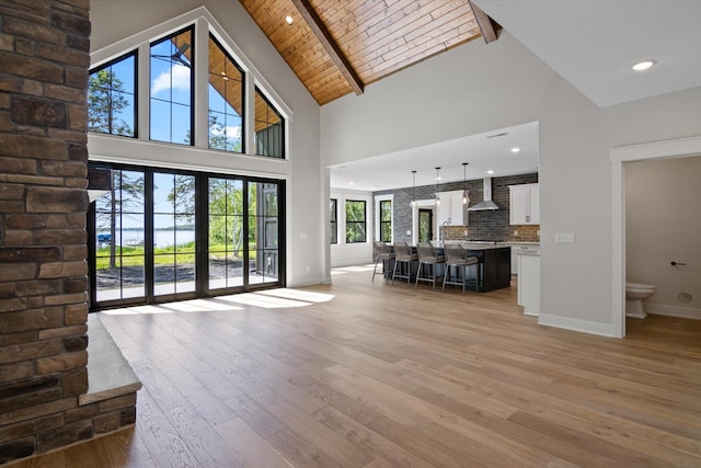 unfurnished living room with high vaulted ceiling, light wood-style flooring, recessed lighting, wooden ceiling, and baseboards