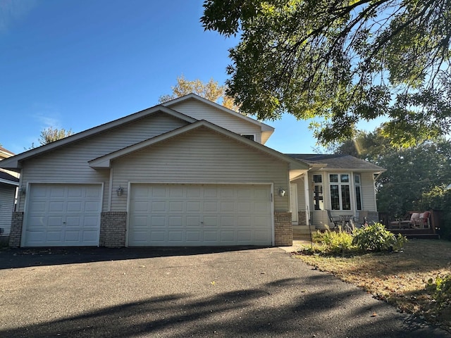 view of front of property featuring aphalt driveway, a garage, and brick siding