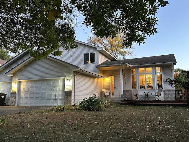 split level home with a garage, brick siding, covered porch, and driveway