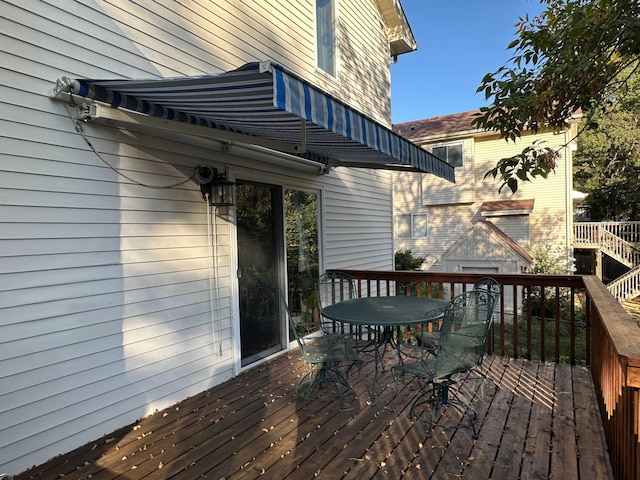 wooden deck with a shed, outdoor dining area, and an outdoor structure