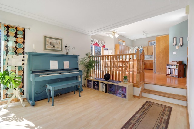 living area featuring ceiling fan, crown molding, and light wood-style floors