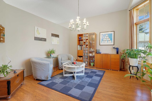 living area featuring a notable chandelier, baseboards, and light wood-type flooring