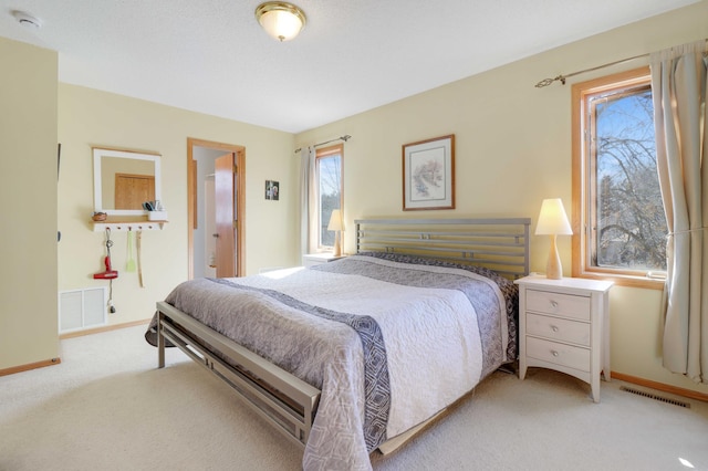 carpeted bedroom with visible vents, multiple windows, and baseboards