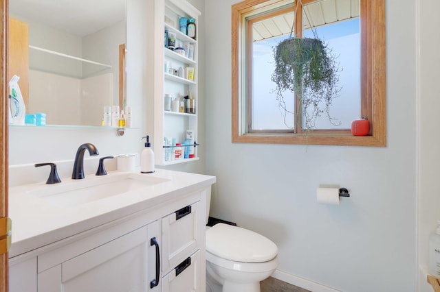 bathroom with toilet, vanity, and baseboards