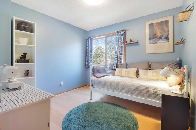 bedroom with baseboards, a textured ceiling, and wood finished floors