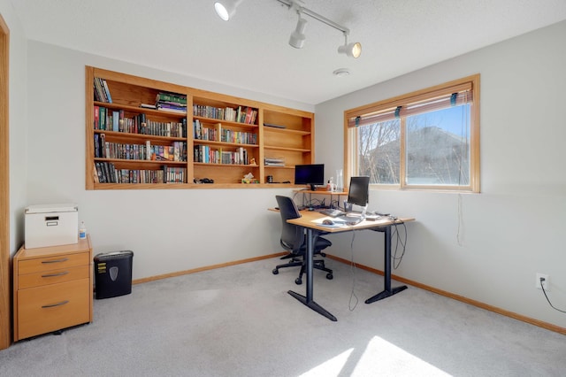 carpeted office featuring rail lighting and baseboards