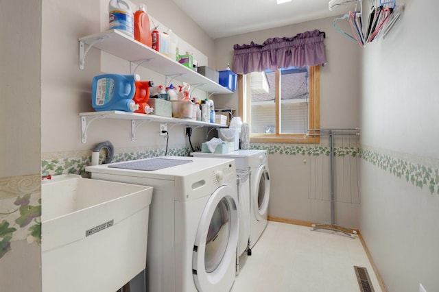 washroom with visible vents, a wainscoted wall, a sink, separate washer and dryer, and laundry area