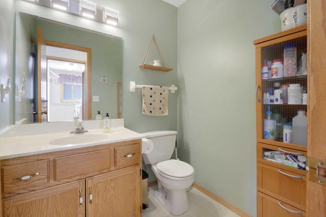 half bathroom featuring vanity, toilet, and baseboards