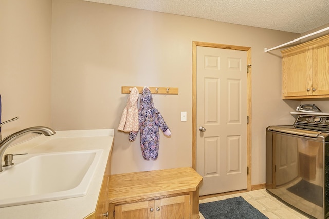 laundry room featuring cabinet space, washer / dryer, a textured ceiling, and a sink