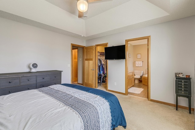 carpeted bedroom featuring a spacious closet, connected bathroom, baseboards, a closet, and a raised ceiling