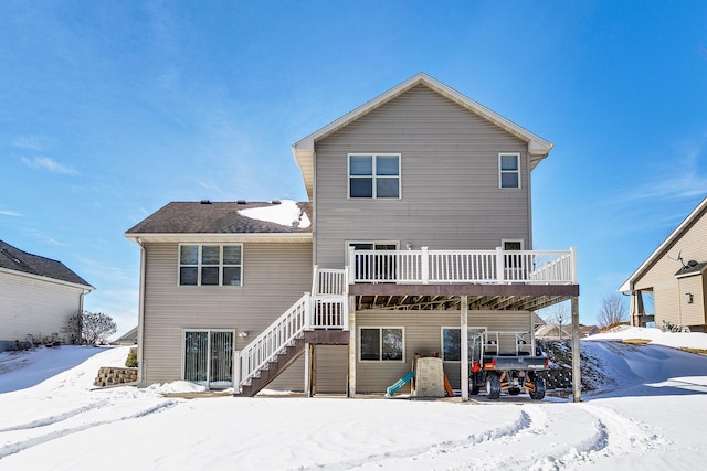 snow covered rear of property featuring stairs and a deck