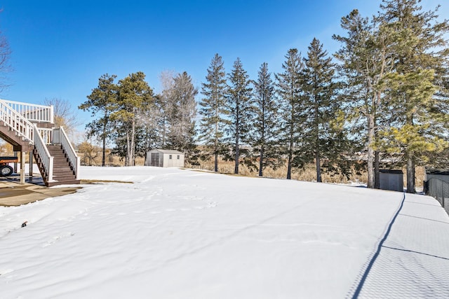 yard covered in snow with stairs, an outbuilding, and a storage unit