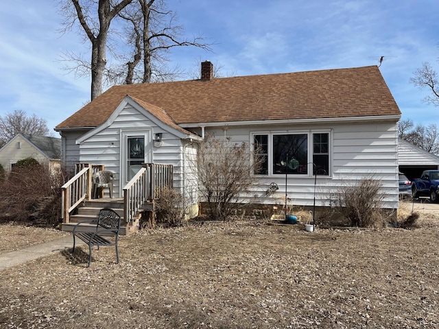 bungalow-style house with roof with shingles and a chimney