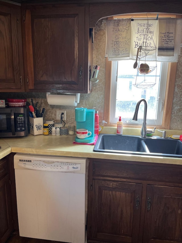 kitchen with light countertops, tasteful backsplash, white dishwasher, and a sink