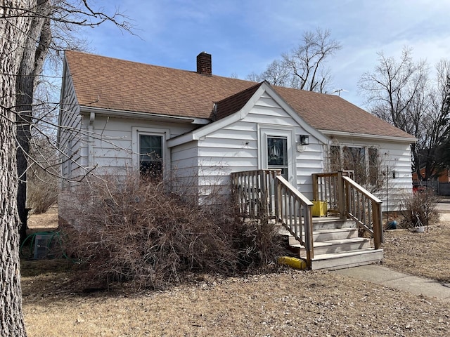 view of front of home with a shingled roof and a chimney