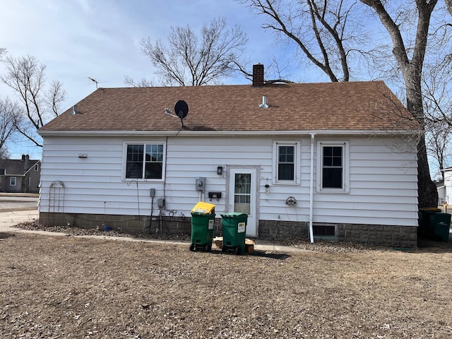 rear view of house with roof with shingles and a chimney