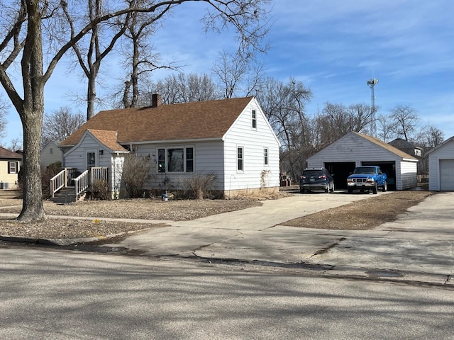 view of front of property featuring a garage, an outdoor structure, a chimney, and a shingled roof