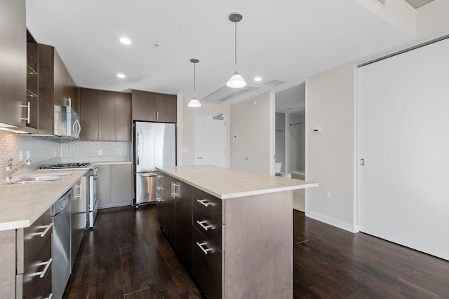 kitchen with a sink, stainless steel appliances, dark wood-style floors, and light countertops