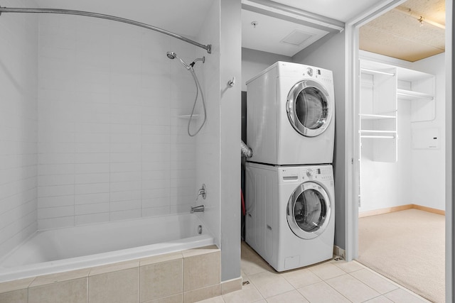 laundry area featuring visible vents, stacked washing maching and dryer, light tile patterned floors, light colored carpet, and laundry area