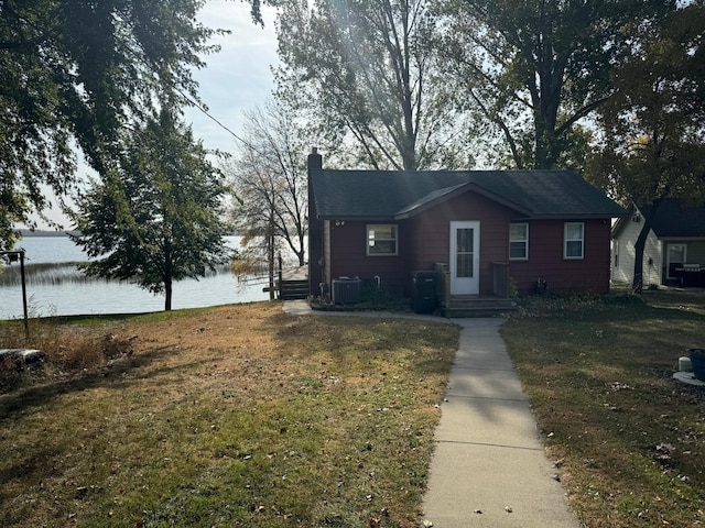 view of front of house with a front lawn, cooling unit, a water view, and a chimney