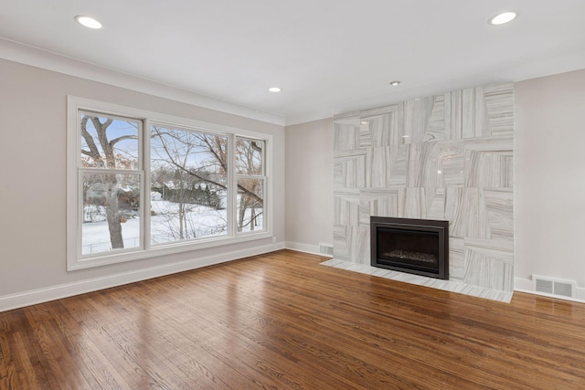 unfurnished living room featuring hardwood / wood-style flooring, a fireplace with flush hearth, recessed lighting, and baseboards