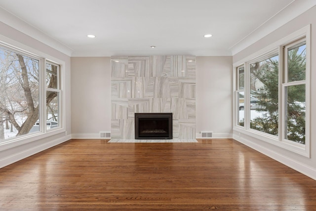 unfurnished living room with visible vents, wood finished floors, baseboards, and a premium fireplace