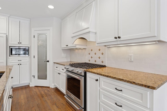 kitchen featuring dark wood-style floors, custom range hood, white cabinets, and appliances with stainless steel finishes