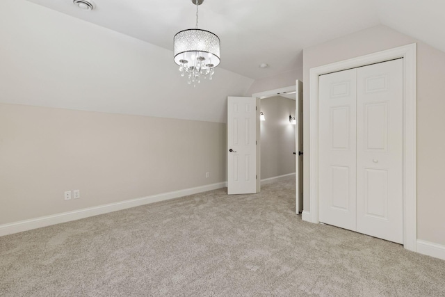 unfurnished bedroom featuring baseboards, lofted ceiling, light colored carpet, and a closet