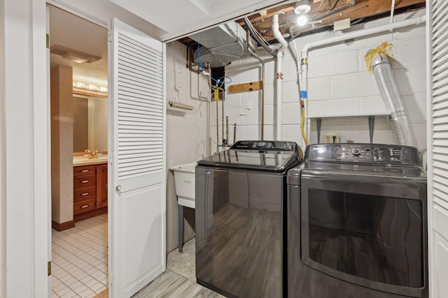 laundry area featuring a sink, laundry area, concrete block wall, and washing machine and clothes dryer