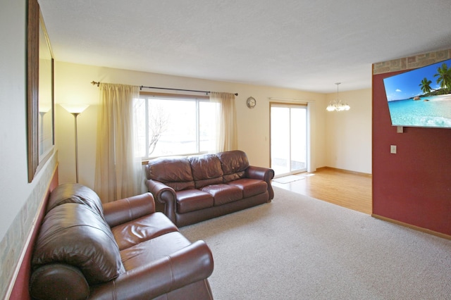 carpeted living area with baseboards and a chandelier