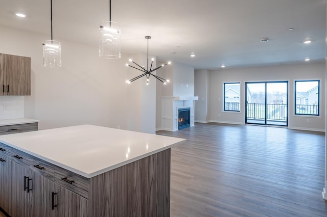 kitchen featuring open floor plan, a center island, light wood-type flooring, and light countertops