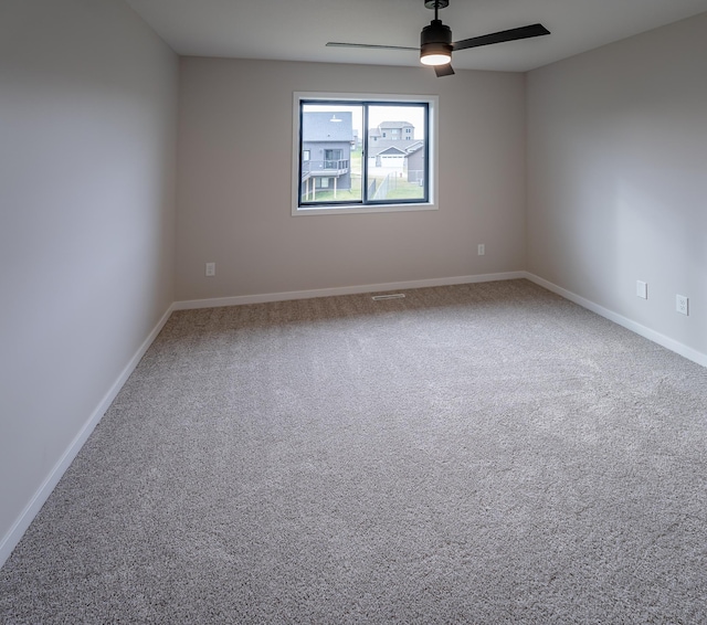 carpeted spare room featuring baseboards and ceiling fan