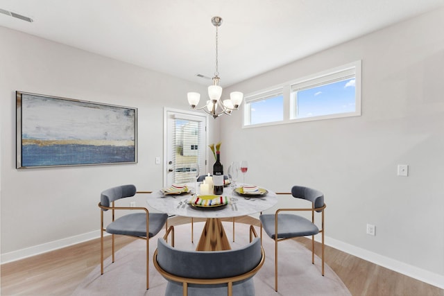 dining space with visible vents, light wood-style floors, a notable chandelier, and baseboards