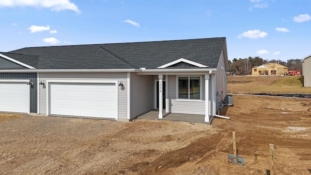 view of front of home featuring driveway, roof with shingles, central AC unit, and an attached garage