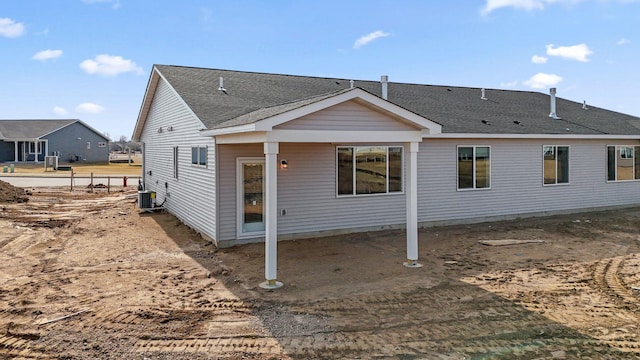 rear view of house with a shingled roof and cooling unit