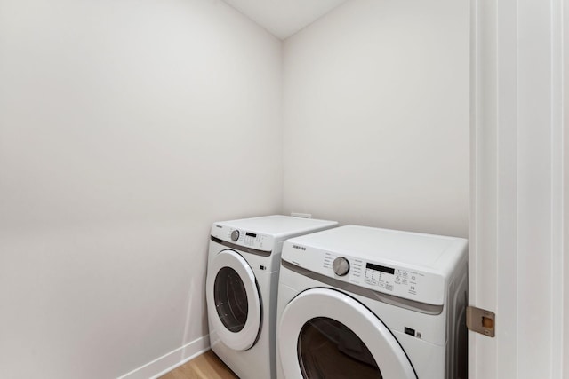 laundry area featuring baseboards, light wood-style flooring, laundry area, and washer and clothes dryer